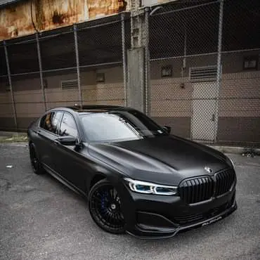 In matt schwarz folierter 4er BMW steht vor Werkstatt-Einfahrt